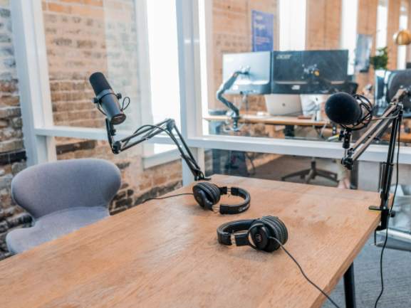 Microphone and headphones on a desk in front of a window 