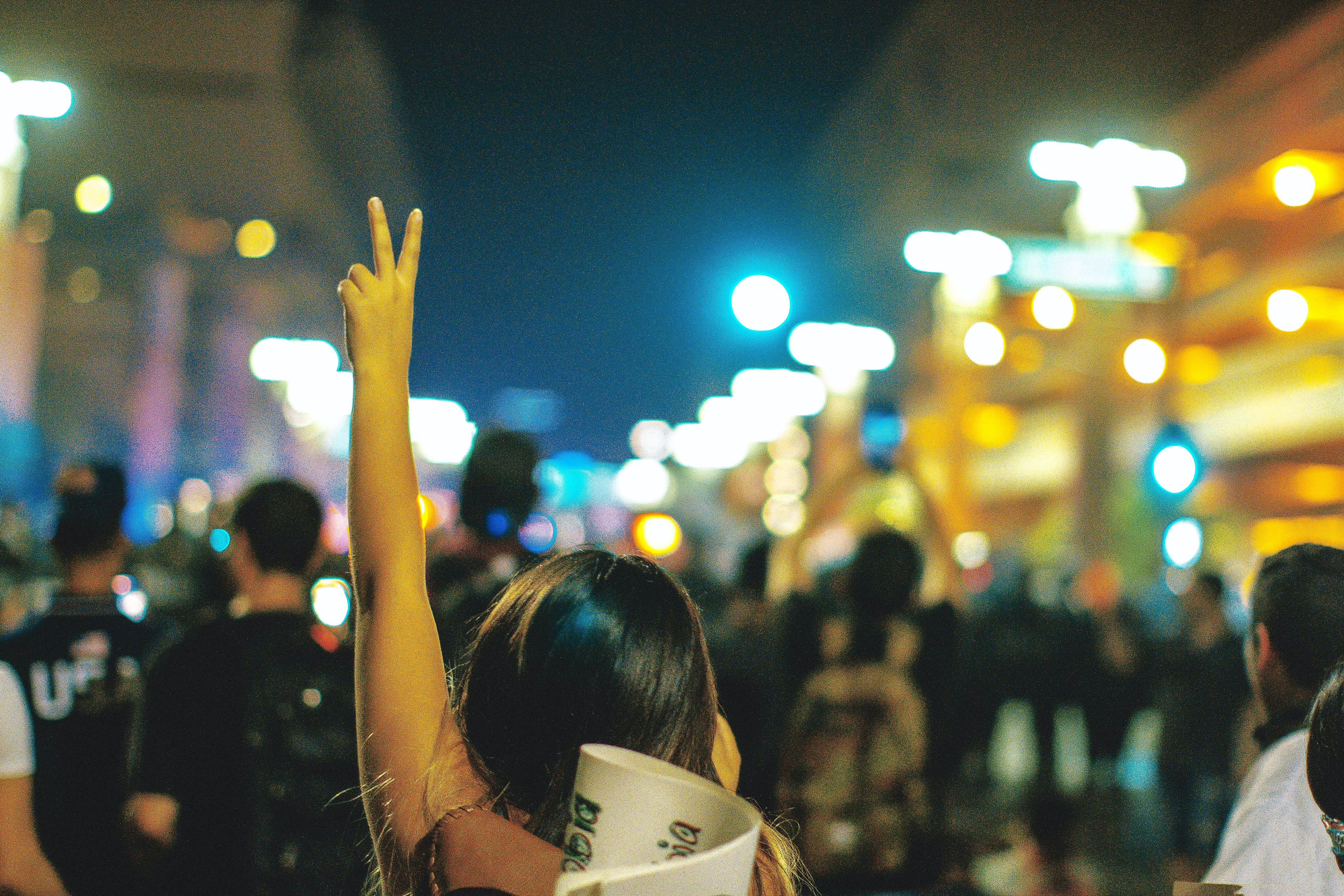 Person at a protest holding up their hands in a peace sign 