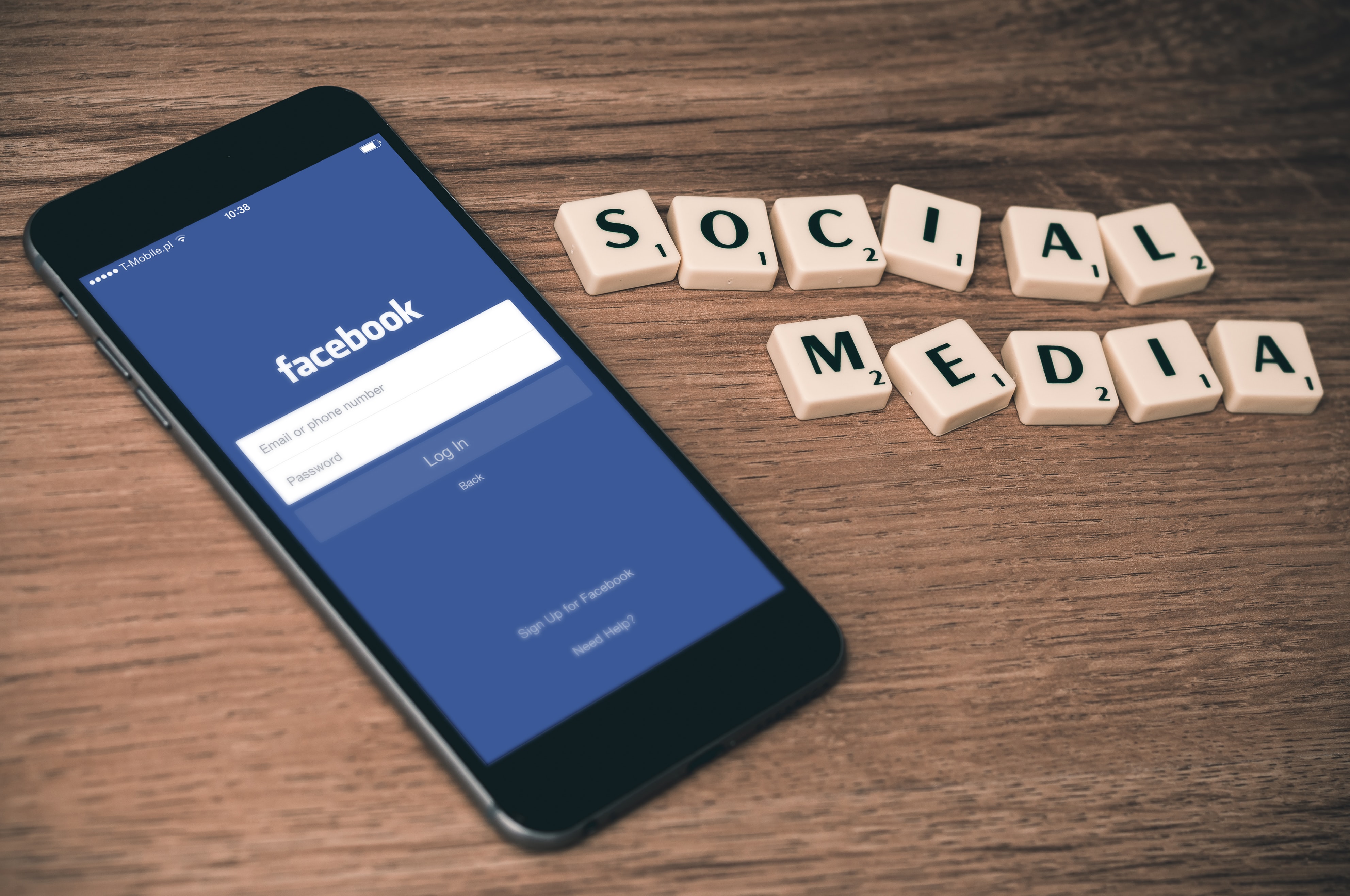 Facebook on a phone with blocks spelling social media on a desk