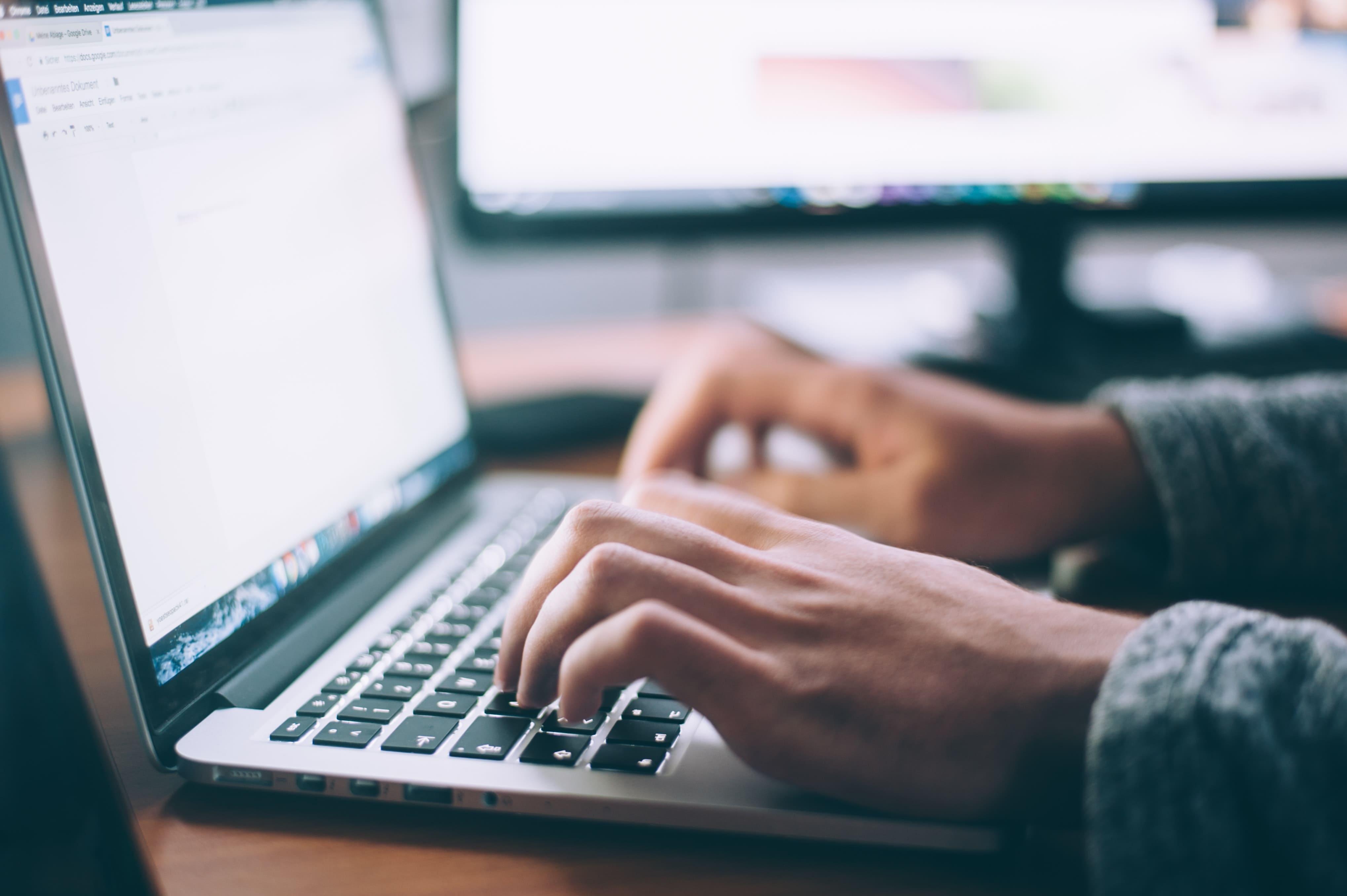 Person typing on a silver laptop